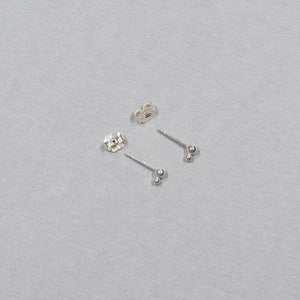 Small silver earrings with two gold stacked beads on a post, shown from side.