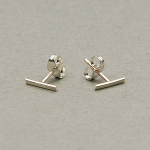 Pair of silver bar earrings on earpost facing out.