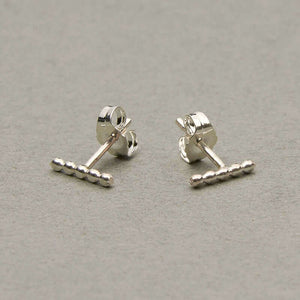 Pair of silver beaded bar earrings on earpost, facing out.