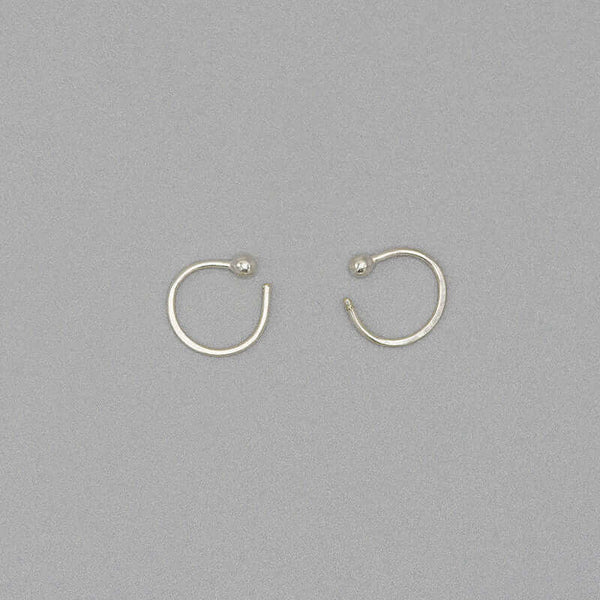 Pair of small silver hoop earring with a tiny ball detail in front, facing in.