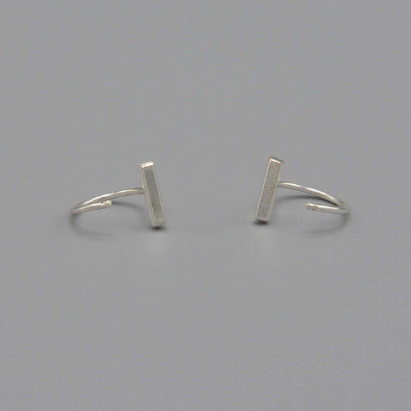 Pair of silver earrings, flat bar in front with curved wire hoop.