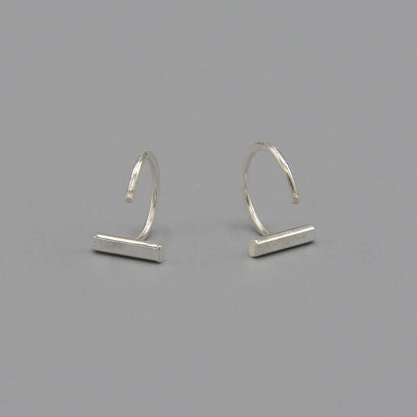 Pair of silver earrings, flat bar in front with curved wire hoop.