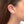 Close up side view of woman wearing gold fern leaf shaped earrings on long earwire.