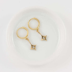 Pair of 4 point gold star earrings on hoop clasp.
