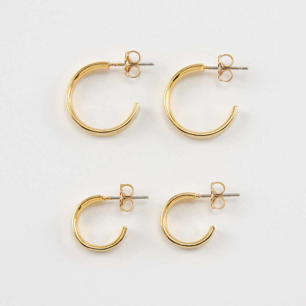 A pair of large and a pair of small gold open hoop earrings on posts.