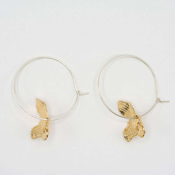 Pair of earrings of gold orchid petals on a silver hoop.