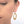 Close up front view of woman wearing pair of gold hammered oval earrings on earwire.