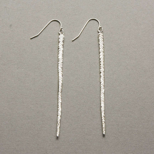 Pair of long silver earrings of thin cast feather on earwire.