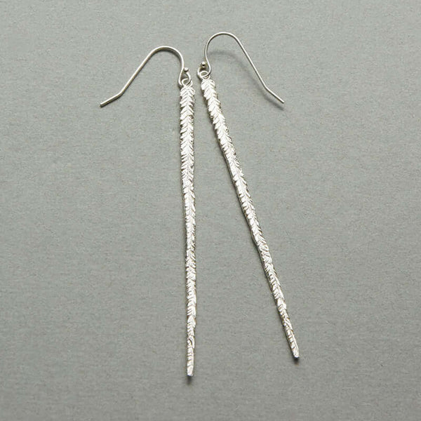 Pair of long silver earrings of thin cast feather on earwire.