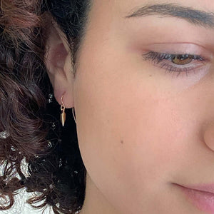 Close-up front view of a pair of gold spike earrings on earwire.