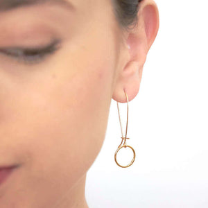 Close-up front view of woman wearing a pair of gold circle earrings on long french earwire.