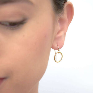 Close-up front view of woman wearing a pair of gold circle earrings on earwire.