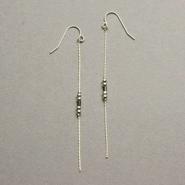 Pair of silver earrings, gold chain with black bead details.