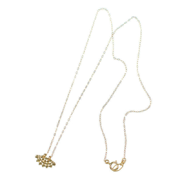 Gold necklace with fan-shaped lace pattern pendant.
