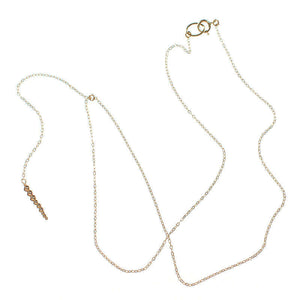 Delicate gold chain necklace with drop pendant of small gold beads, laid out showing clasp.