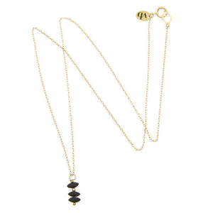Delicate gold chain necklace with small black beads as pendant, full length showing clasp.