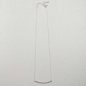 Close-up of silver chain necklace with curved beaded bar pendant, full length showing clasp.