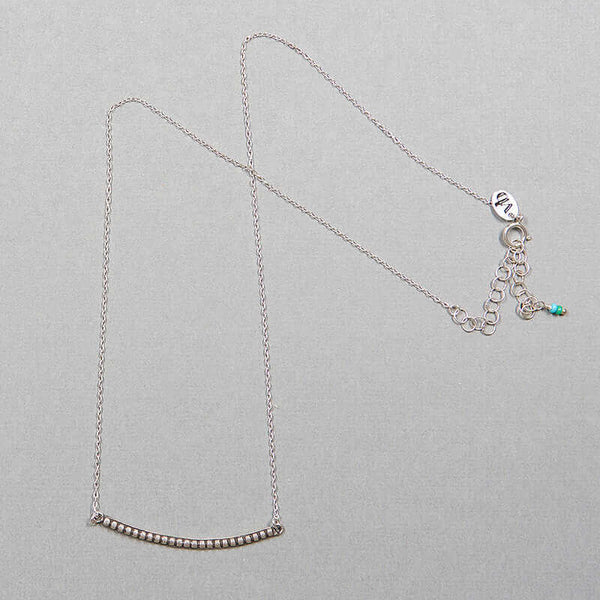 Close-up of silver chain necklace with curved beaded bar pendant, full length showing clasp.