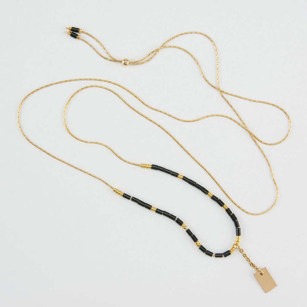 Delicate adjustable gold necklace with black and gold beads and gold rectangle drop pendant.