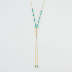 Close-up of delicate gold necklace with turquoise and gold beads shown reverse with adjuster bead.