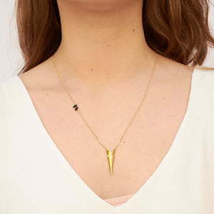 Woman wearing gold chain necklace with chevron pendant.