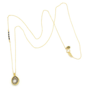 Delicate gold chain necklace with carved round pendant, shown full length.
