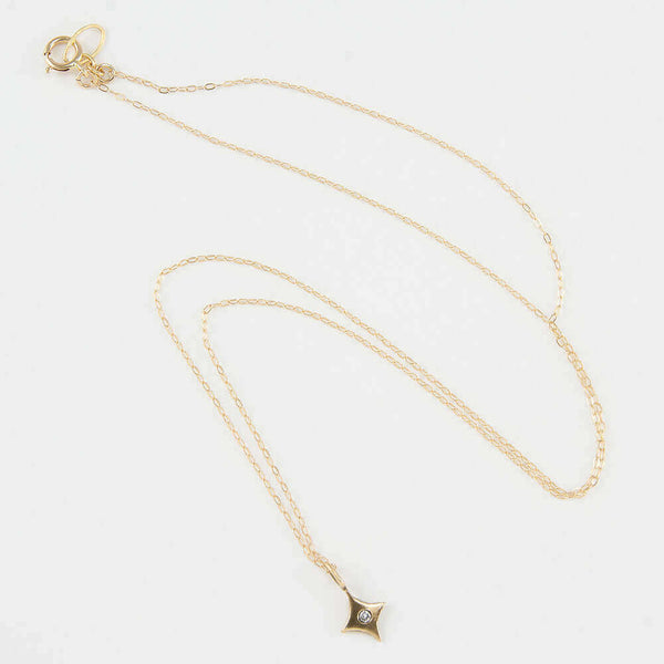 Close-up of delicate gold chain necklace with 4 point gold star pendant with inset diamond..