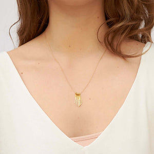 Woman wearing delicate gold chain necklace with hand-hammered gold frill pendant.