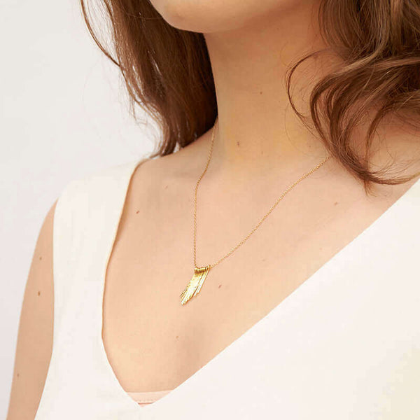 Woman wearing delicate gold chain necklace with hand-hammered gold frill pendant, shown at side angle.