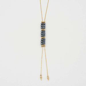 Close-up of gold chain necklace with pendant of double rows of dark pearls and gold beads, that slide to adjust length.