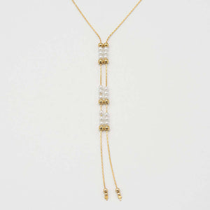 Close-up of gold chain necklace with pendant of double rows of white pearls and gold beads, that slide to adjust length.