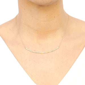 Woman wearing gold chain necklace with cast twisted rope bar pendant.
