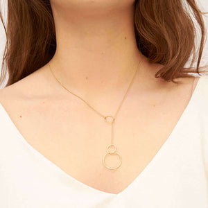 Woman wearing gold chain necklace with hoops are at end that slide for adjustment.