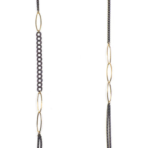 Close-up of long black oxidized silver multi-chain necklace with gold link details along chain.