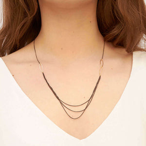 Woman wearing short black oxidized silver multi-chain necklace with gold link details along chain.