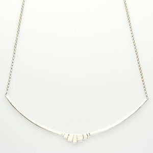 Close-up of silver necklace with curved bar pendant with geometric native motif.