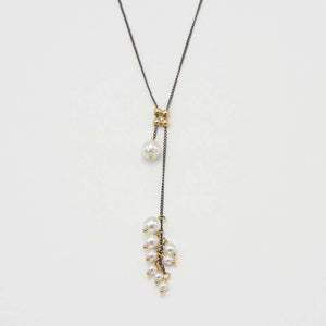 Close-up of black oxidized silver chain necklace with gold slider beads and pearls at the ends.