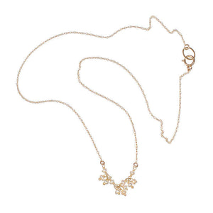 Delicate gold necklace with small pearls as pendant.