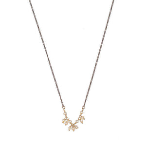 Close-up of delicate black oxidized necklace with small pearls as pendant.