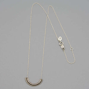 Silver necklace with beaded curved pendant.