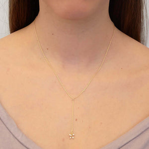 Woman wearing dainty gold necklace with pendant of simple drop chain and  tiny pearls.