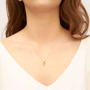 Woman wearing delicate gold chain necklace with tiny findings as pendant.