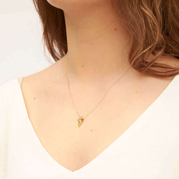 Woman wearing delicate gold chain necklace with tiny findings as pendant, shown side angle.