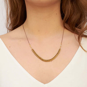 Woman wearing black oxidized chain necklace with brass curb chain on bottom.