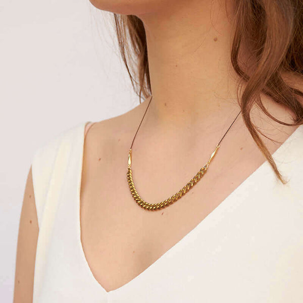 Woman wearing black oxidized chain necklace with brass curb chain on bottom, shown side angle.