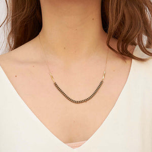 Woman wearing gold chain necklace with vintage curb chain on bottom.