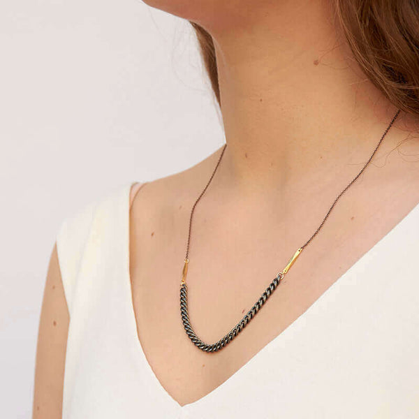 Woman wearing black oxidized chain necklace with vintage curb chain on bottom, shown side angle.