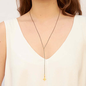 Woman wearing dark bead chain necklace with small geometric cross shaped pendant and slider.