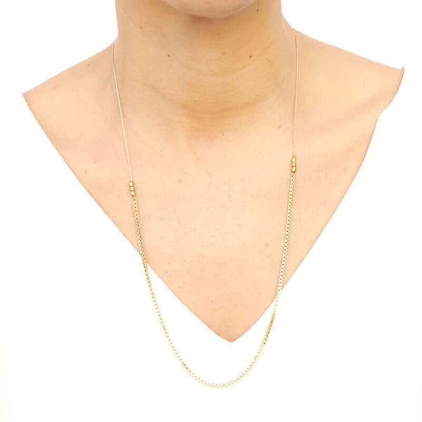 Woman wearing delicate gold chain necklace with box chain front, and slider for clasp, worn short