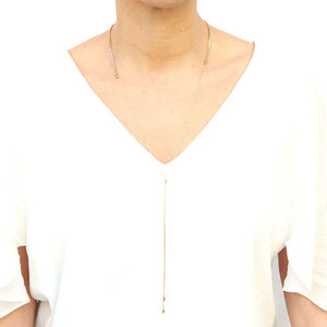 Woman wearing delicate gold chain necklace with box chain front, and slider for clasp, worn with clasp in front.